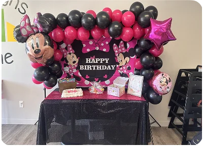 An image of a birthday setup with Minnie Mouse balloons and party decorations.
